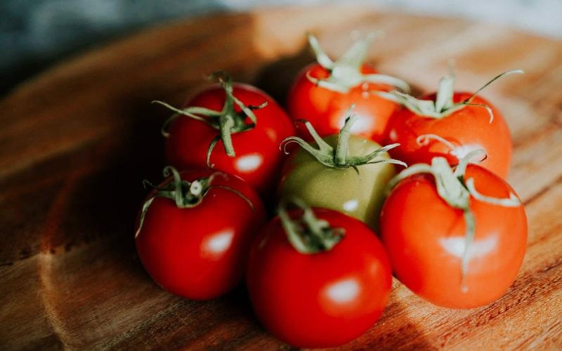 bunch of tomatoes on a wooden plate